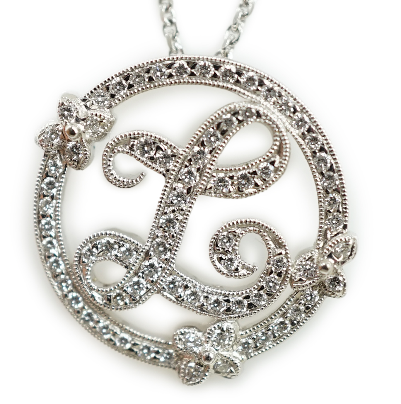 A modern 18k white gold and diamond chip cluster set circular initial 'L' pendant, on an 18k white gold necklace